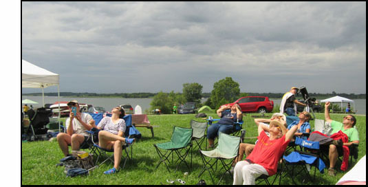 Picture shows 12 lawnchairs with 7 people, all but one leaning far back and looking up at the sky (Erick looks like his is taking a picture of us with his smartphone).  David is standing behind them, looking into his telescope which is aimed at the sky.